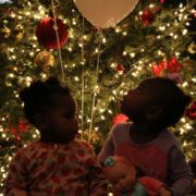 Twochildren sitting underneath a Christmas tree