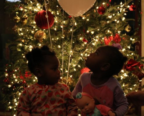 Twochildren sitting underneath a Christmas tree