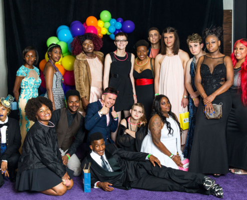 Covenant House Youth in suits and dresses at 2019 Pride Prom with an assortment of rainbow balloons in the backdrop.