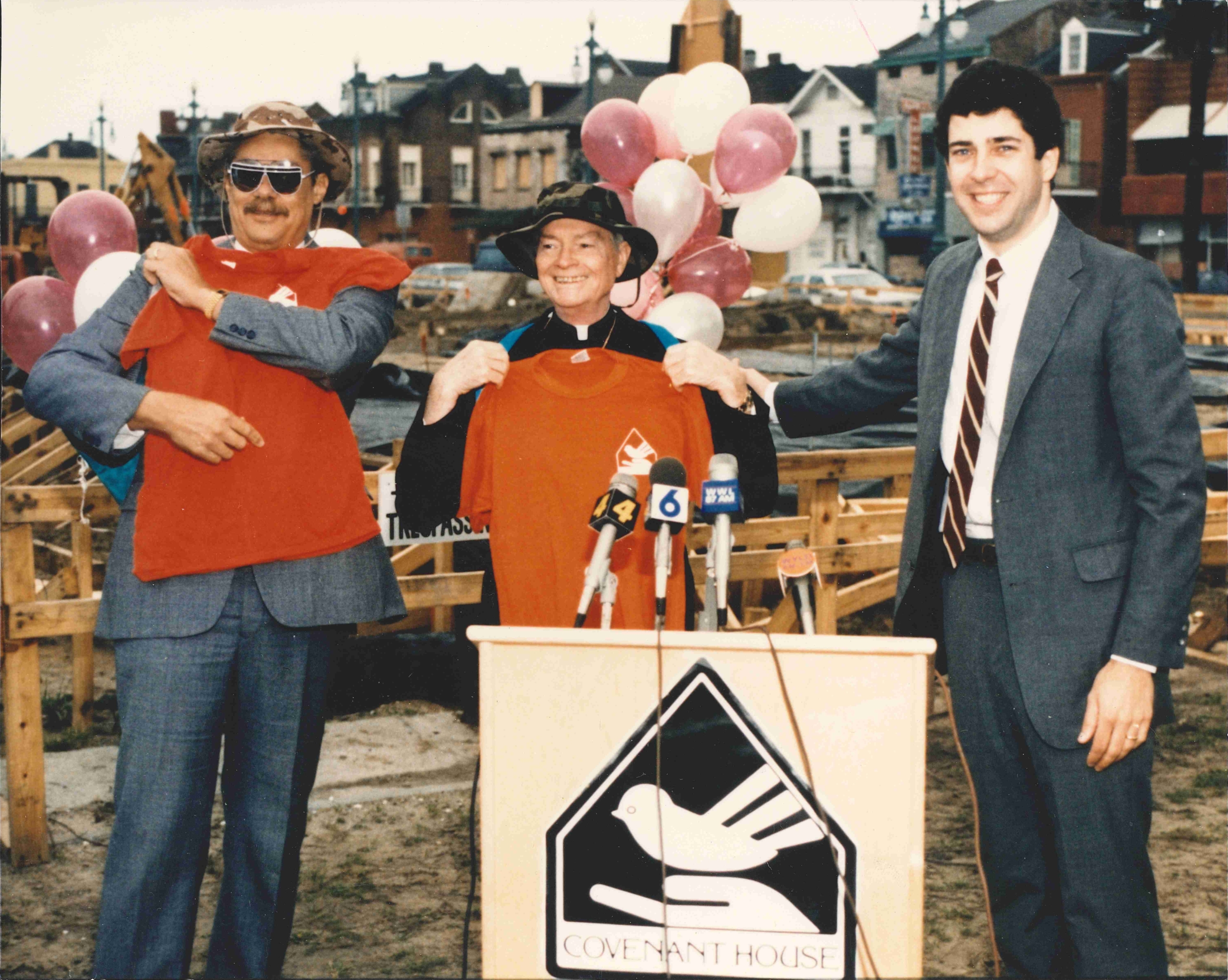 Photo of three men standing behind a podium during the construction of the Covenant House