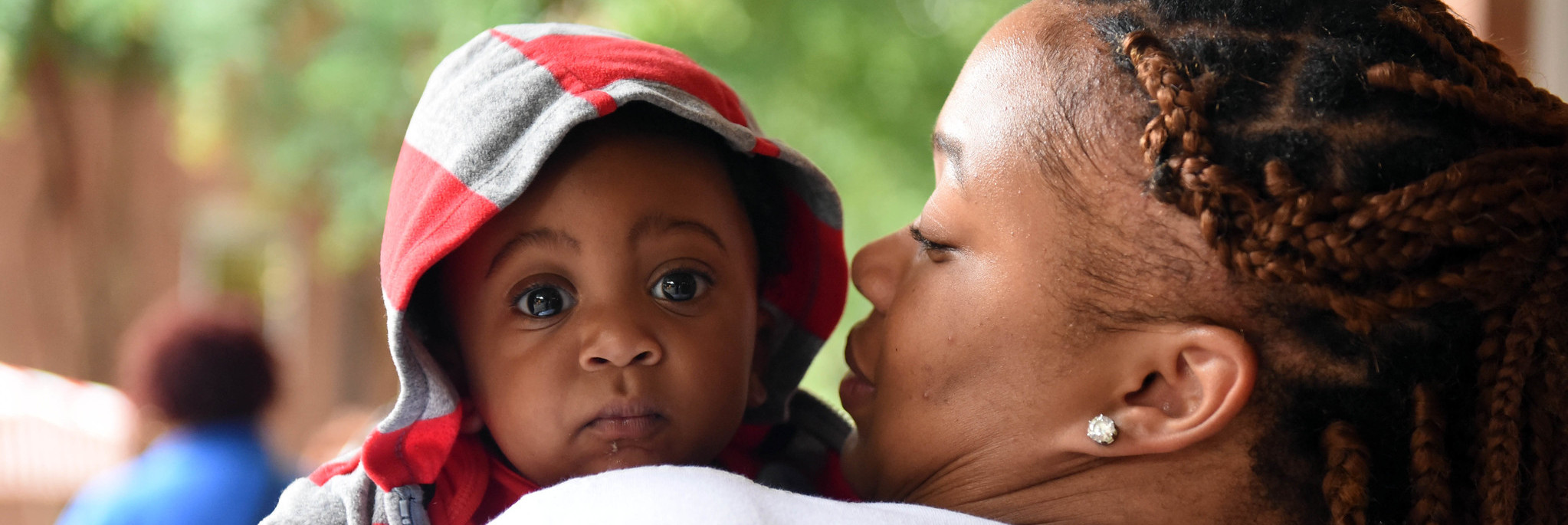 Baby carried off by mother looks back at the camera