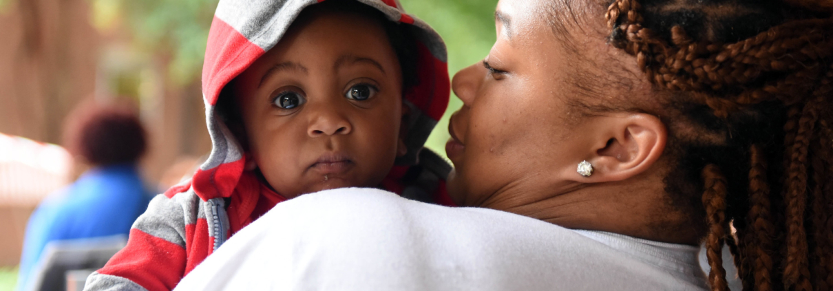 Baby carried off by mother looks back at the camera