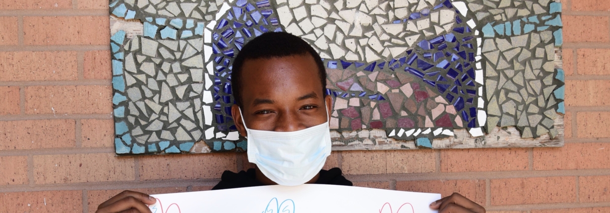Teen wearing a mask while holding a "Thank you" sign