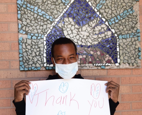 Teen wearing a mask while holding a "Thank you" sign