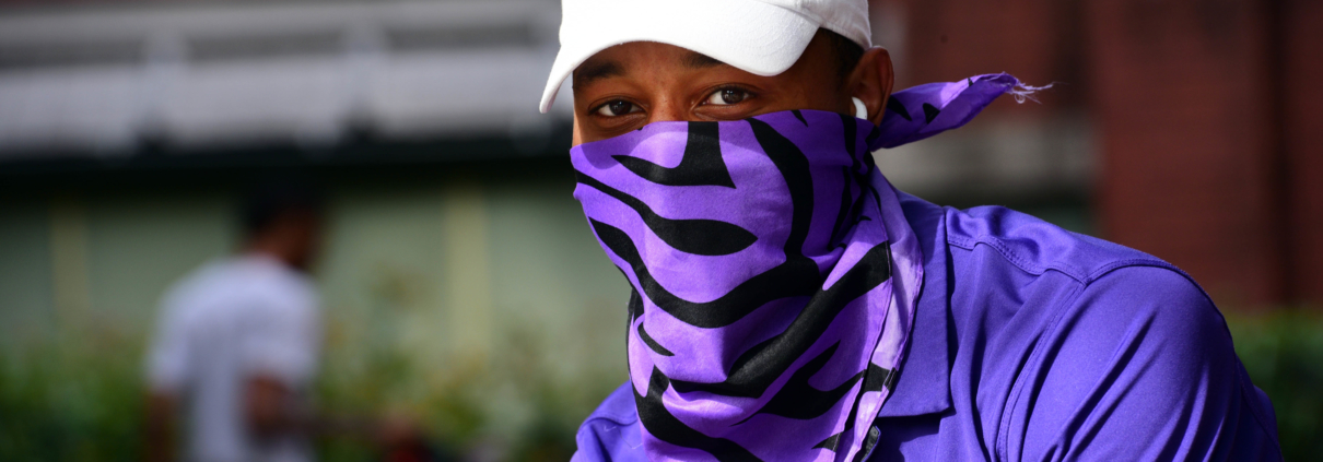 Man poses for camera wearing LSU polo and purple tiger neck gaiter