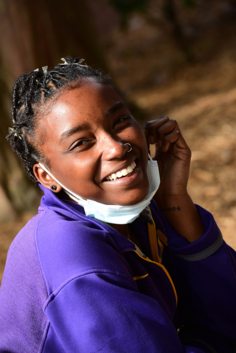 Woman smiles while looking at camera and taking off mask