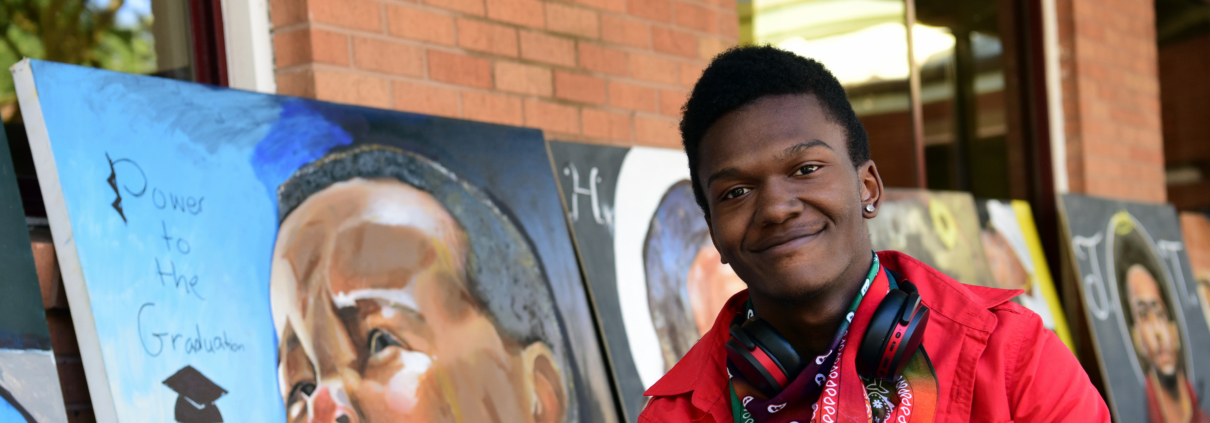 Close up of Elijah in front of some of his artwork
