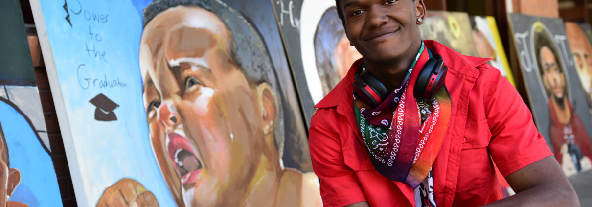 Close up of Elijah in front of some of his artwork