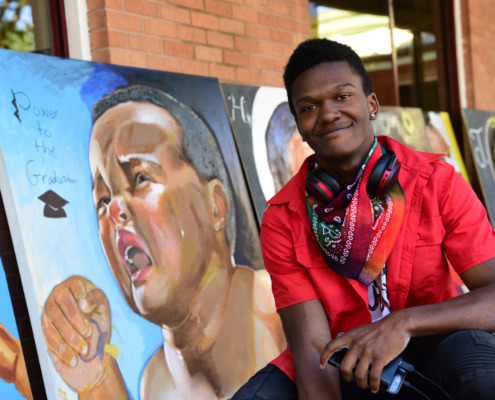 Close up of Elijah in front of some of his artwork