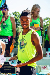 Jakiya smiles after winning second place in the race, holding his prizes and wearing a medal.