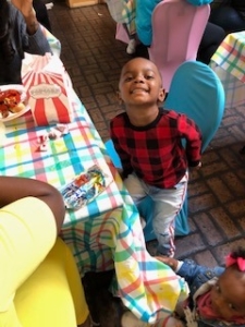 A young boy in a black and red shirt smiles.